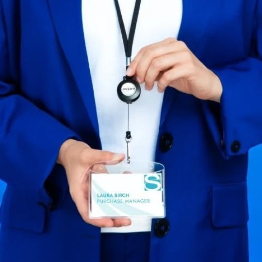 A man in a blue suit with a lanyard with a name tag around his neck