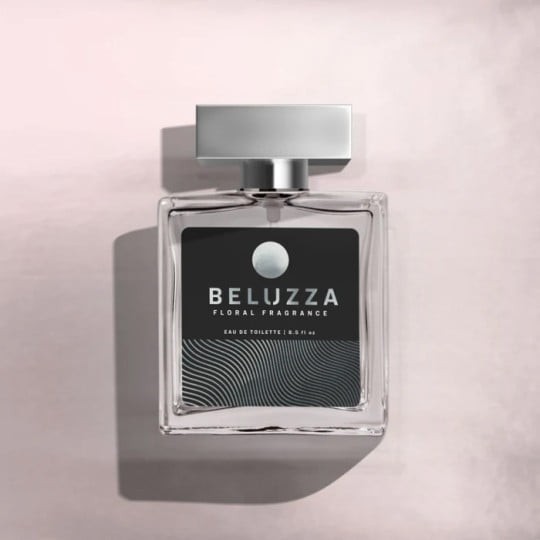 A top-down view of a square glass bottle of Beluzza Floral Fragrance eau de toilette. The bottle has a silver cap and a black label with a silver wavy pattern, set against a pale pink textured surface.
