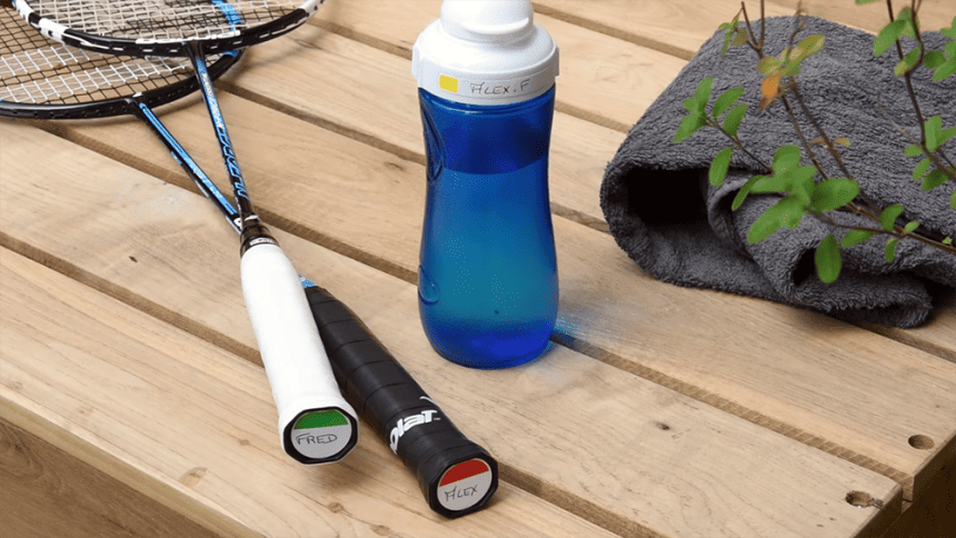 Wooden table with a blue water bottle and two badminton rackets on it