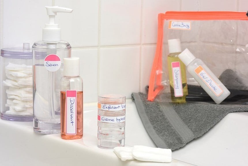 Cosmetic products in travel-size bottles with handwritten descriptions—one on the table, the other wrapped in a transparent plastic bag.