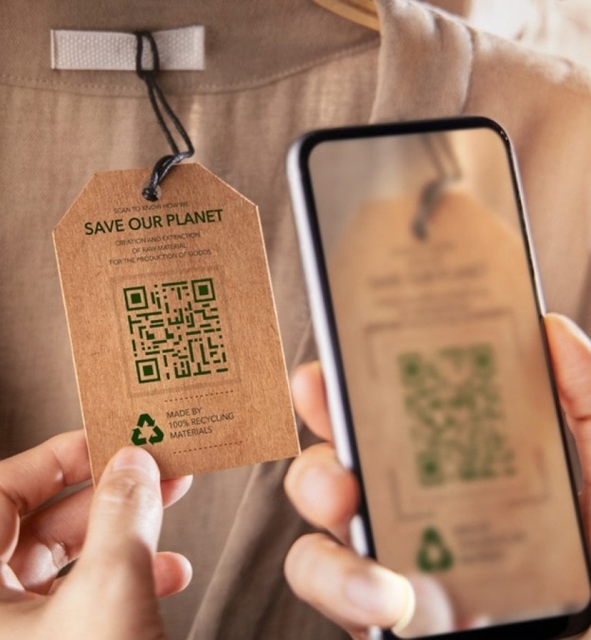 A person uses a smartphone to scan a QR code on a sustainable clothing tag that reads "Save Our Planet" and includes a recycling symbol.