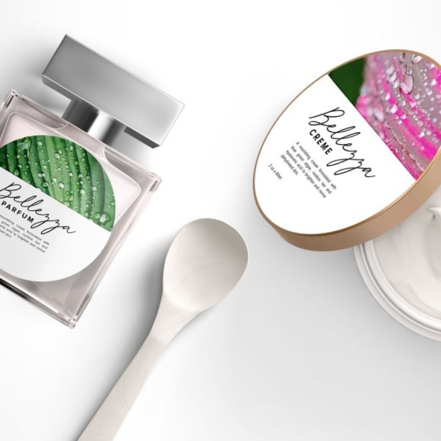 An elegant product display: a square “Bellezza” perfume bottle with a label featuring a green leaf motif, alongside an open jar of cream from the same brand next to a small white spoon.