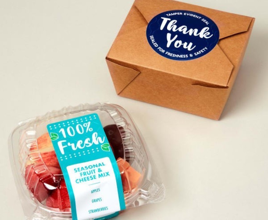 A small container of fresh fruit with a "100% Fresh" label, next to a brown takeout box sealed with a blue "Thank You" tamper-evident sticker.