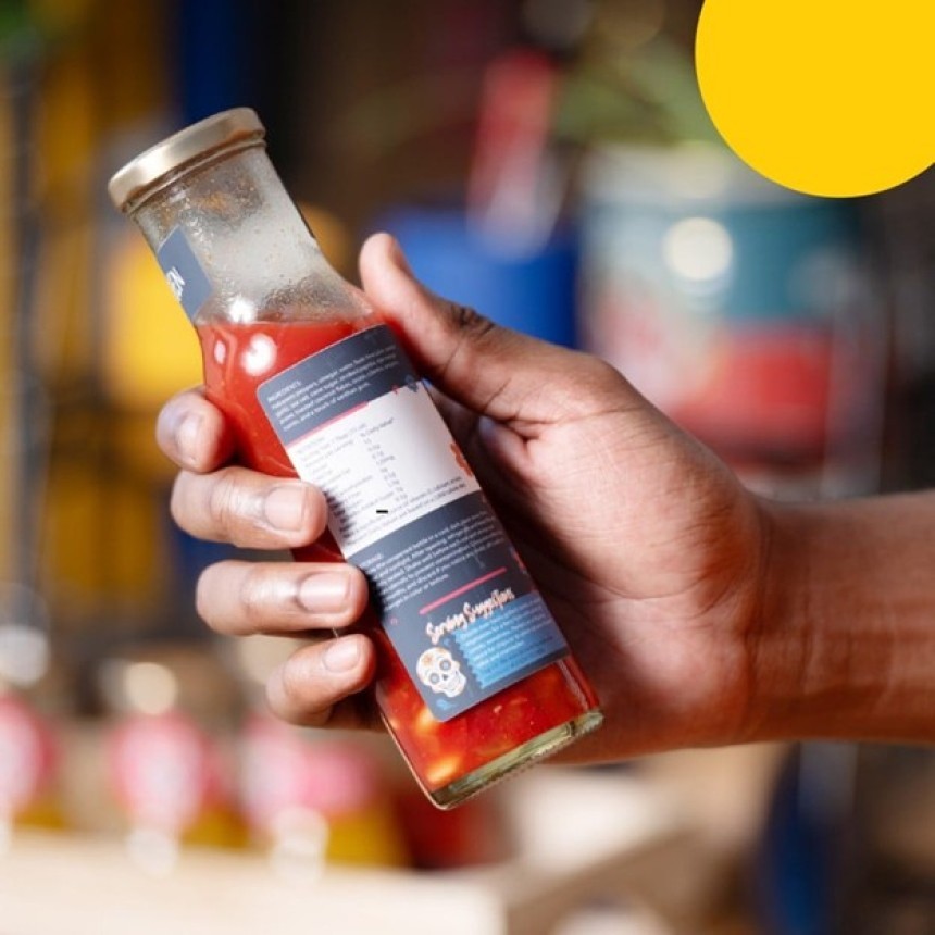 A hand holding a bottle of sauce, which has a product label with nutritional information.